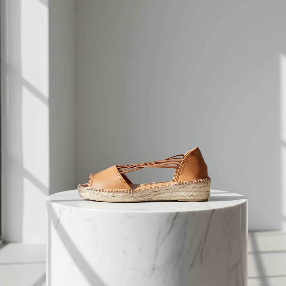 Brown sandal with espadrille sole on a white marble surface