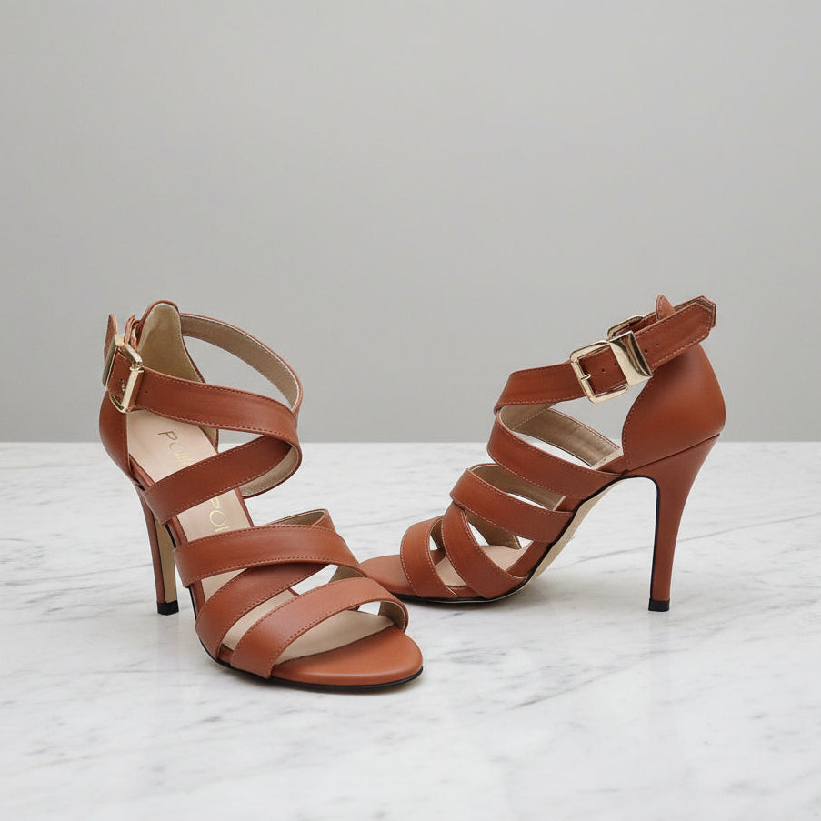 Pair of brown high-heeled sandals on a light gray background