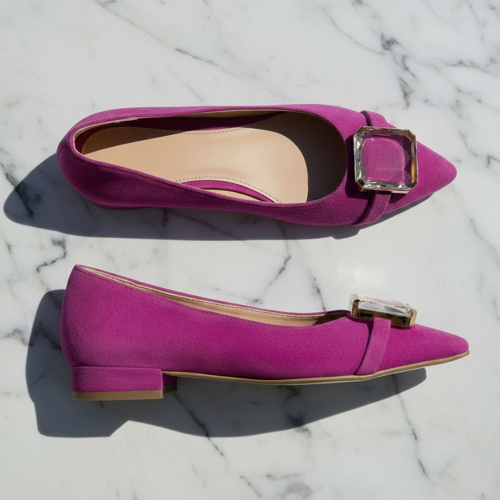 Pair of magenta petite ballerina shoes with a decorative buckle on a marble surface