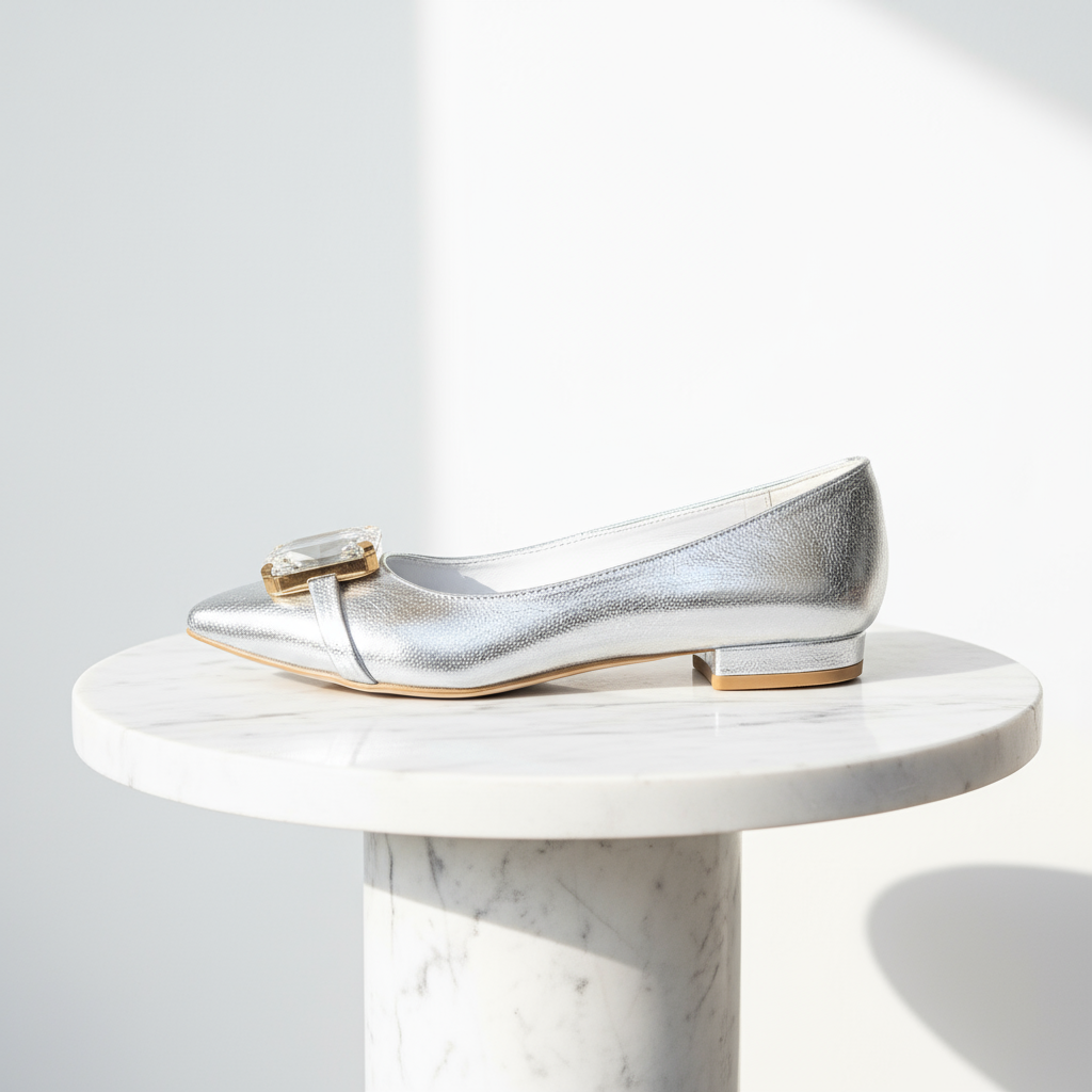 Silver pointed-toe shoe with a gold accent on a white background