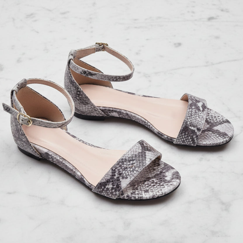 Pair of snake print sandals on a light gray background
