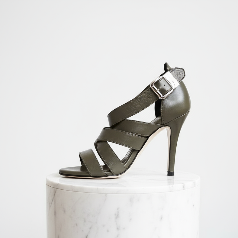 Green high-heeled sandal on a white marble pedestal with a white background
