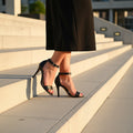 MARIS petite black leather sandals worn on feet showing ankle strap and slim 9cm heel on rug