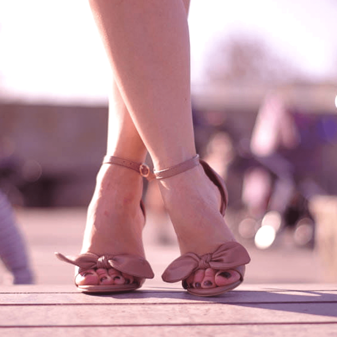 A woman wearing ankle strap heeled sandals in beige leather
