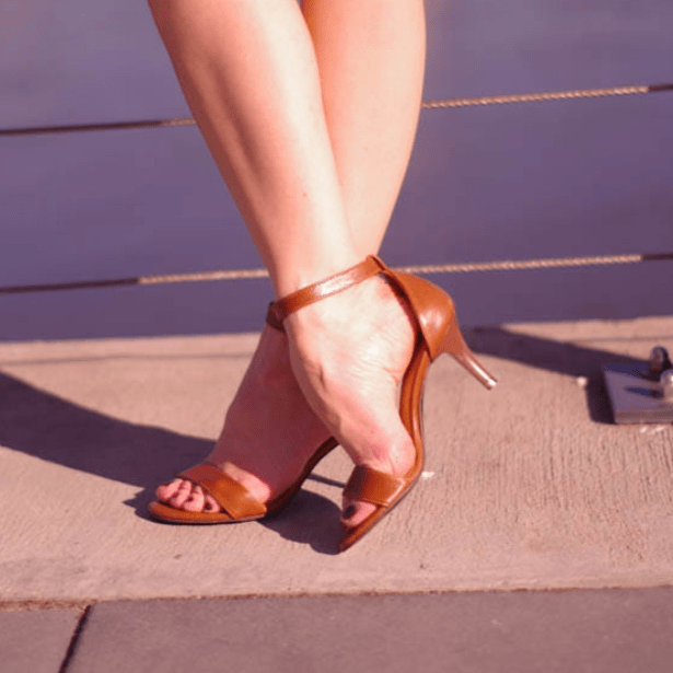 A lady wearing ankle strap sandals in brown leather