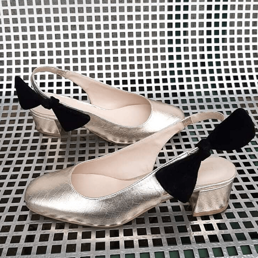 Gold slingback shoes with a black bow