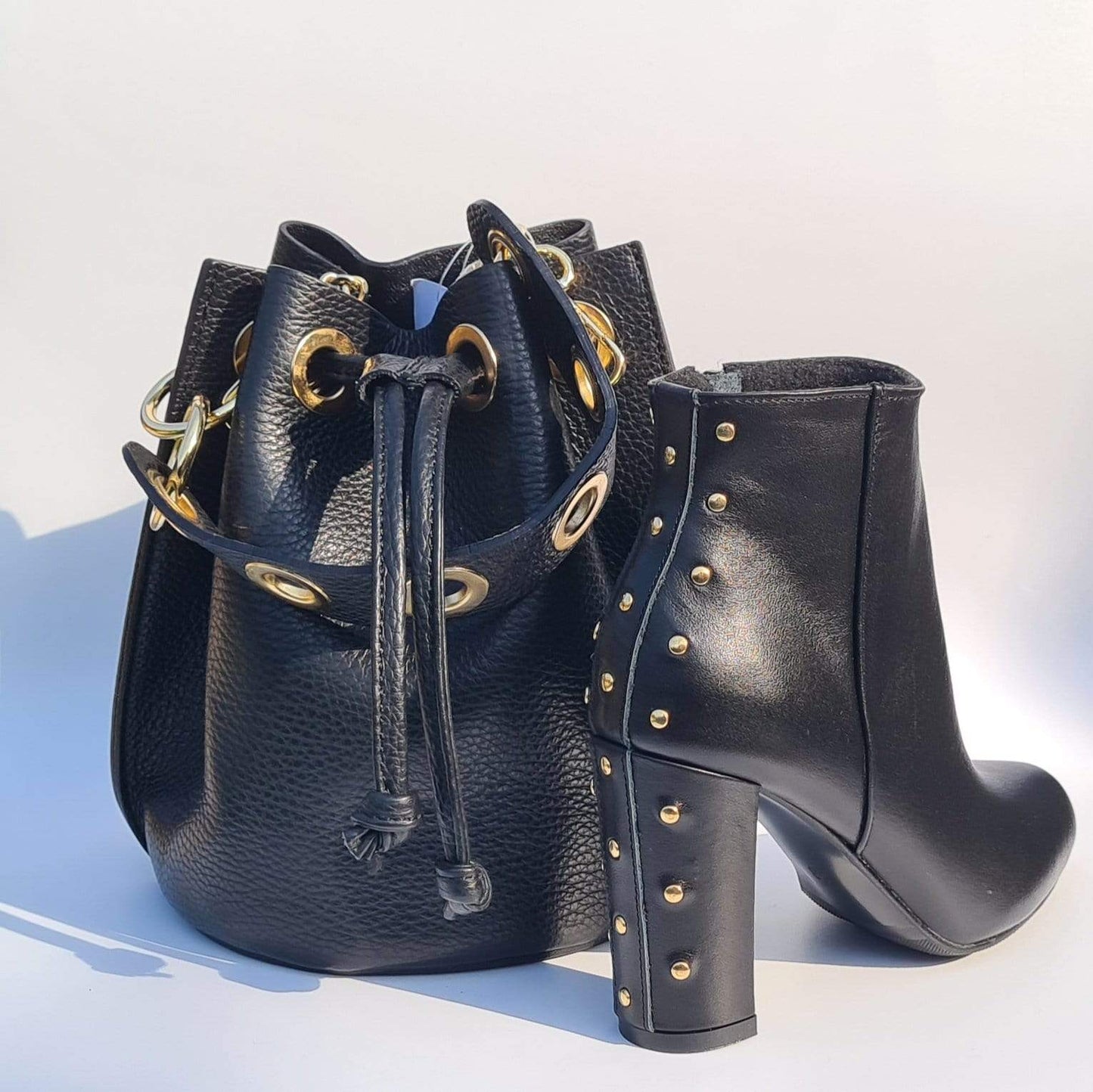 Black leather bucket bag and a matching leather ankle boot with gold studs
