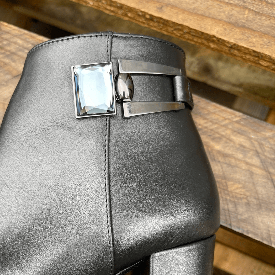 Metal hardware adorning black leather ankle boots