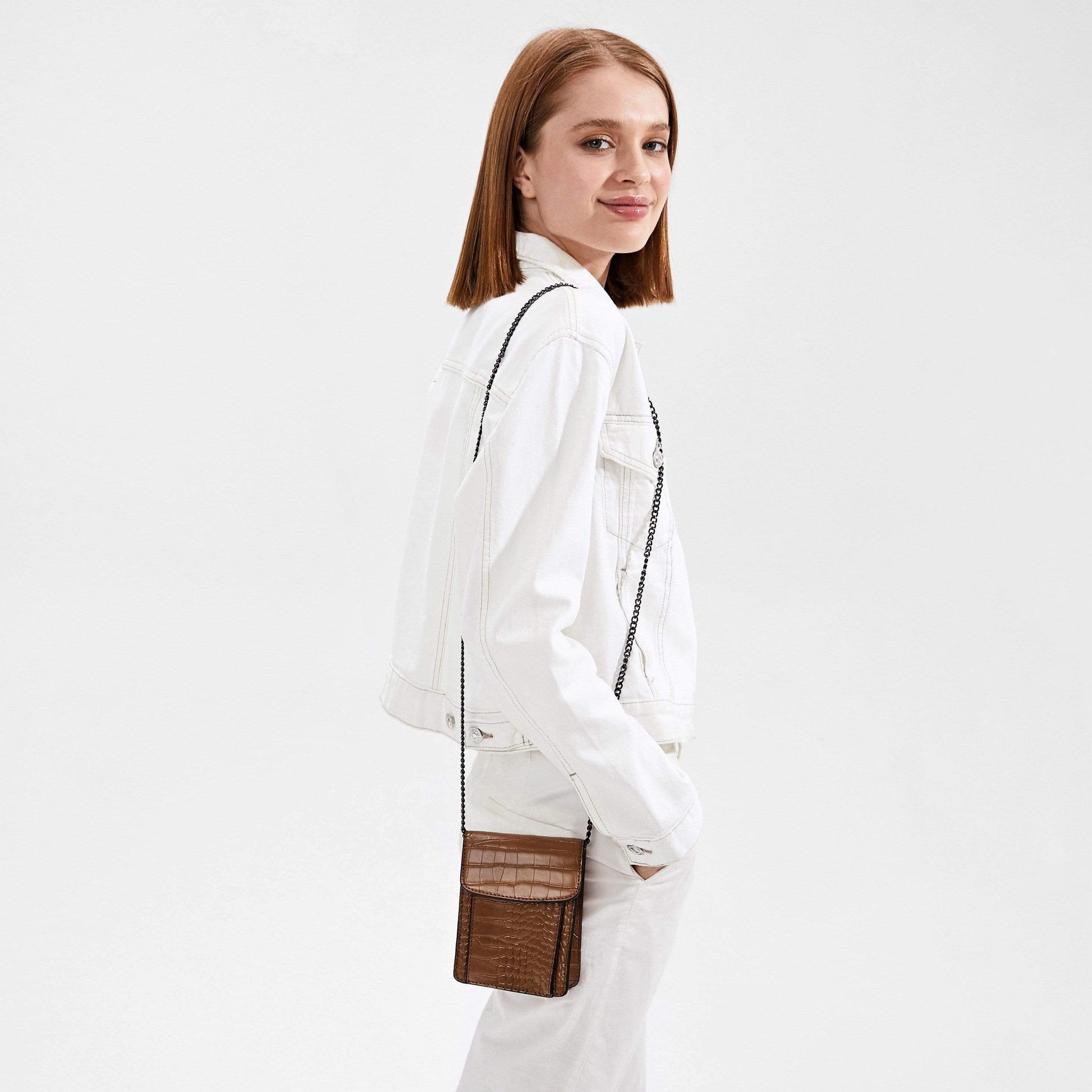 Woman in white wearing a bron shoulder bag.